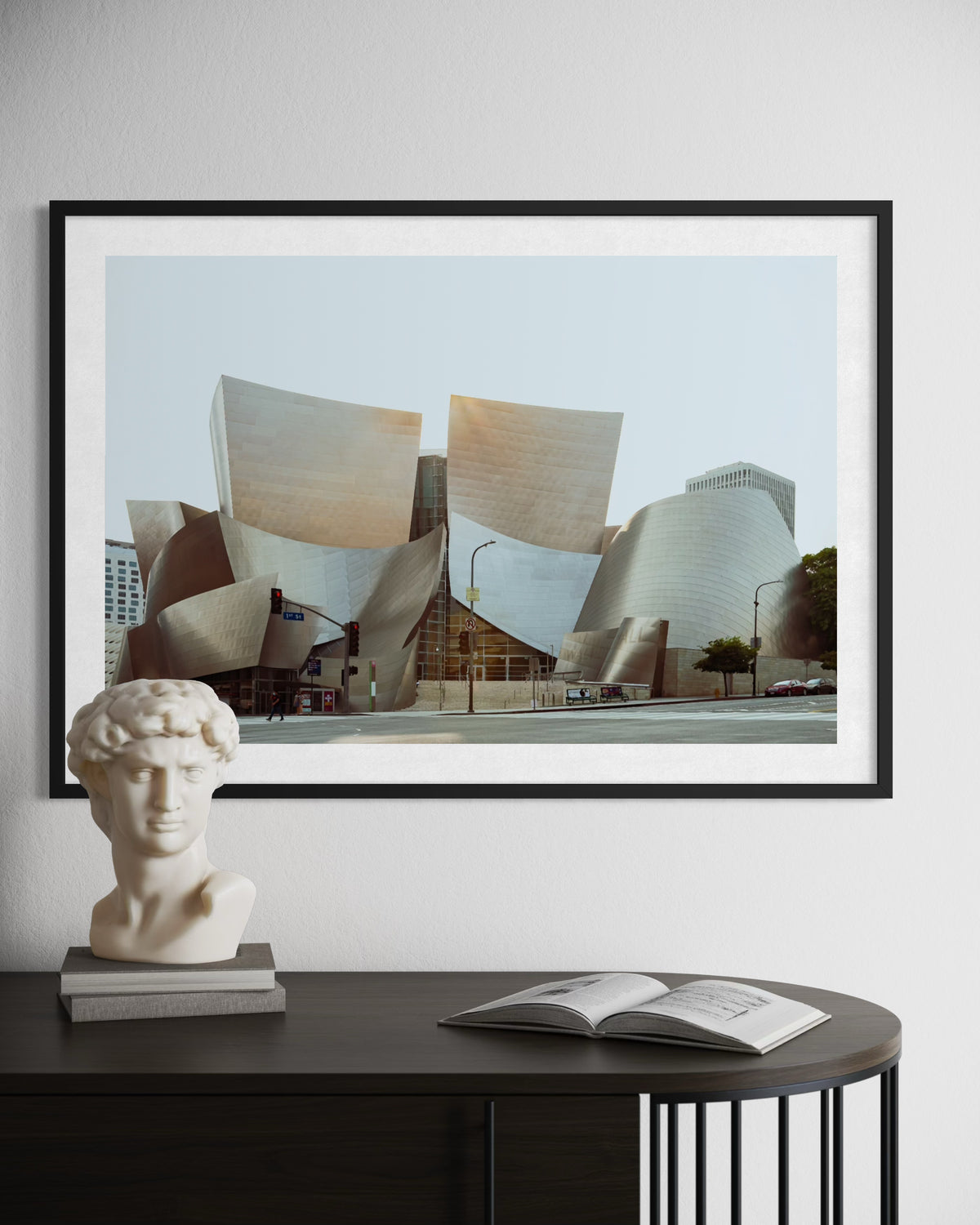 Framed photo of Los Angeles’ Walt Disney Concert Hall above a table with bust and book in a modern, minimal room.