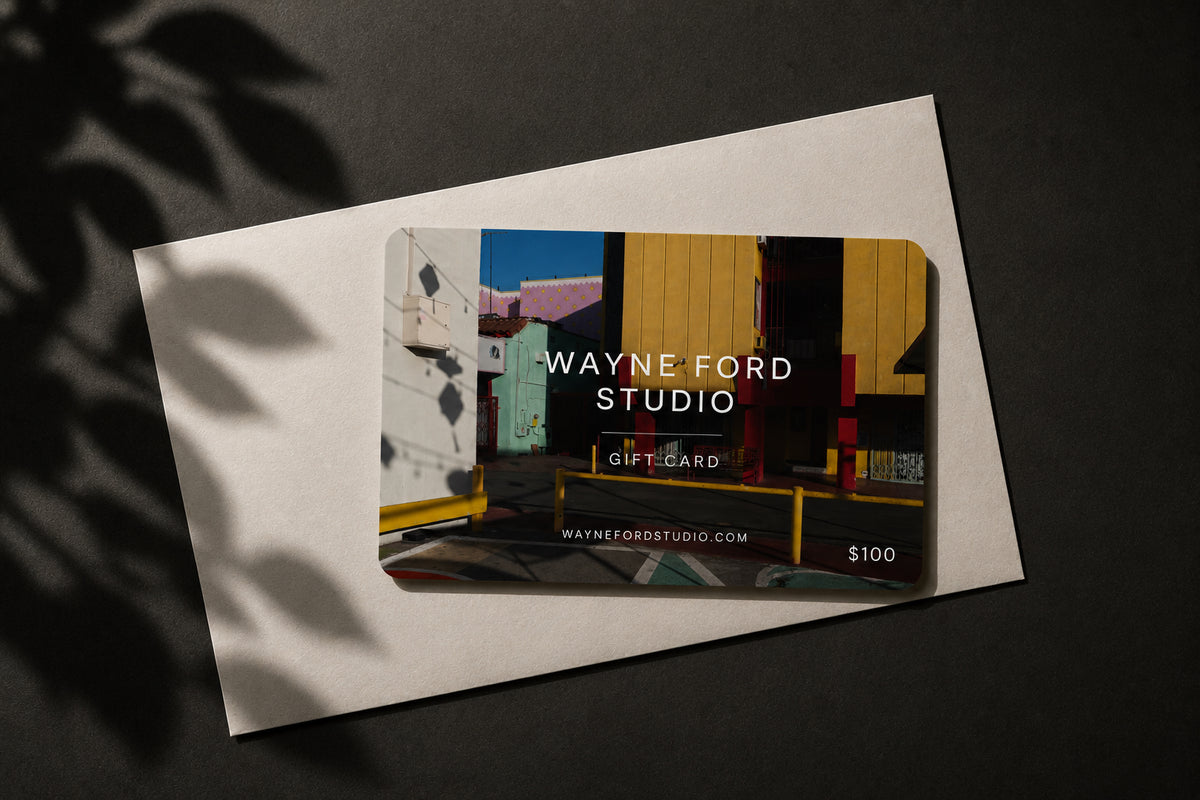 Wayne Ford Studio gift card on a white envelope, featuring a vivid urban building photograph in the background.