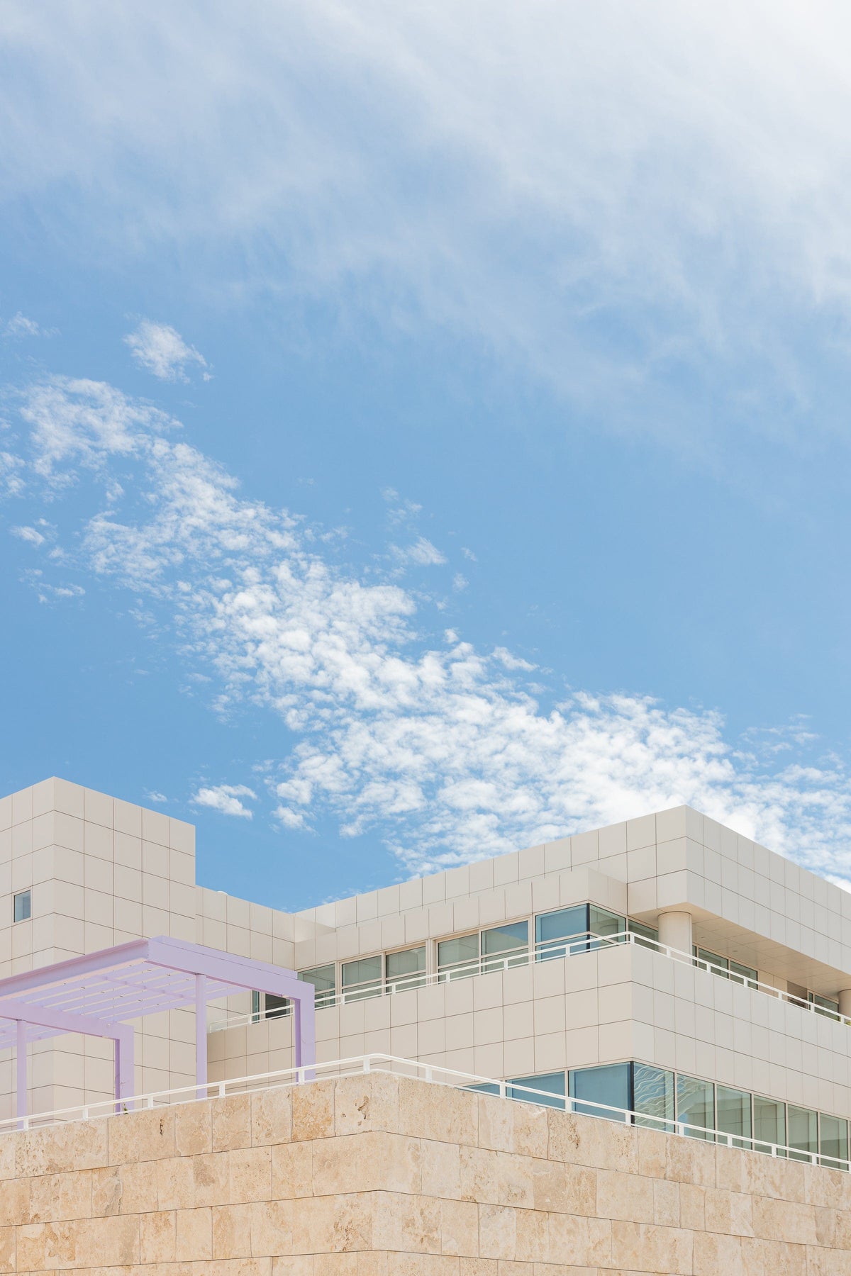 Modern white architecture, glass windows, and travertine details at Getty Center in Los Angeles beneath a blue sky.