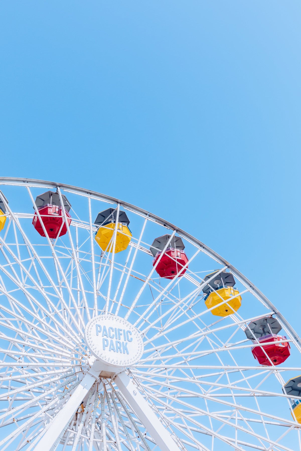 Ferris wheel with colorful gondolas set against a bright summer sky in Santa Monica, California.