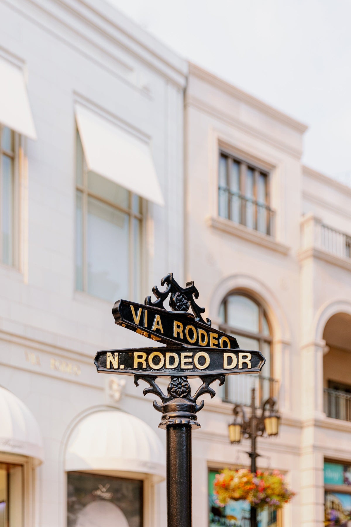 Rodeo Drive street sign with white luxury buildings in Beverly Hills under a clear, sunny sky.