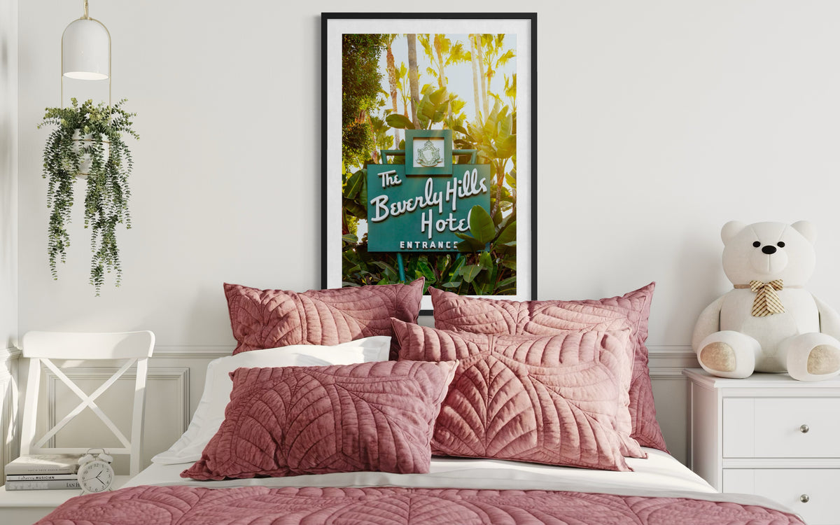 Pink pillows on a bed, Beverly Hills Hotel Sign print above, teddy bear on the nightstand in a Los Angeles bedroom.