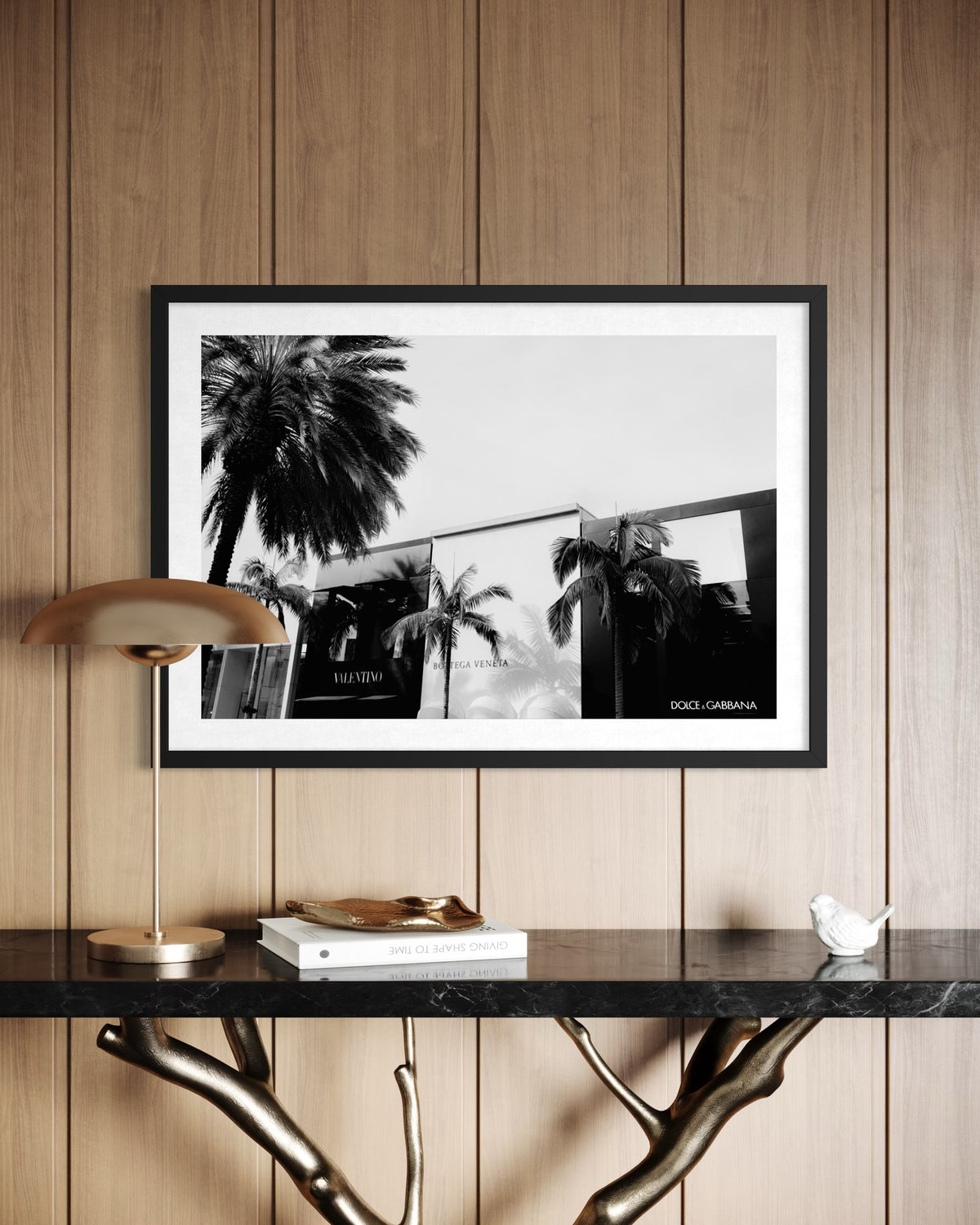 Framed Beverly Hills Luxe photo displayed above a console table with lamp, books, and small sculpture.