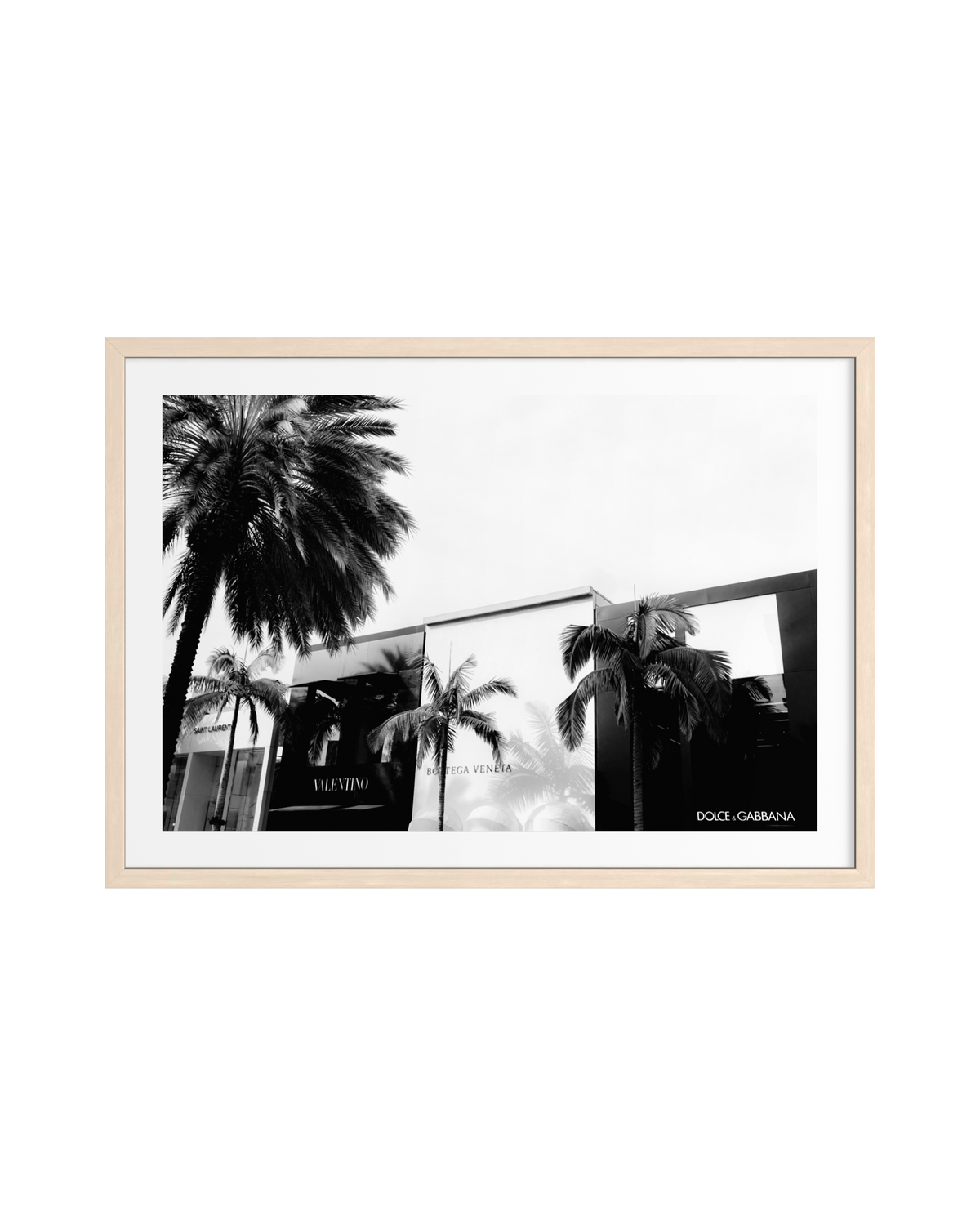 Black and white photo of a Beverly Hills building with palm trees and Dolce & Gabbana signs, in light wood frame.