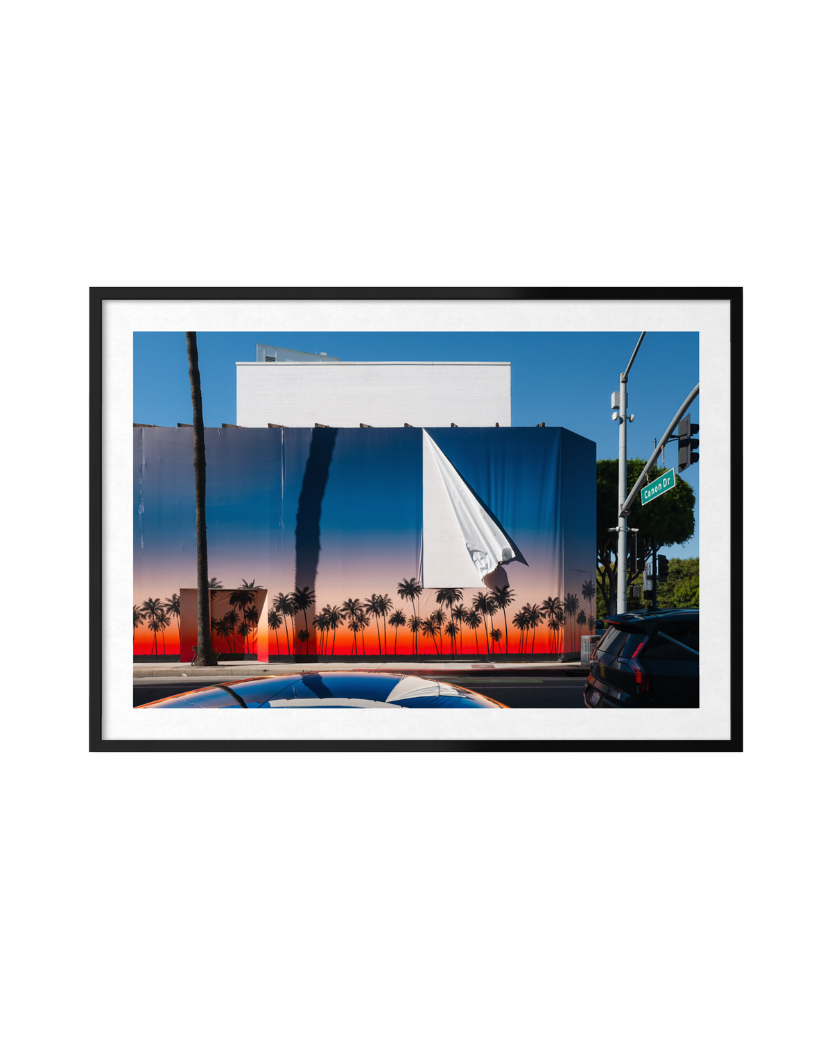 A billboard of sunset palms peeling away to a white surface on a Beverly Hills street.