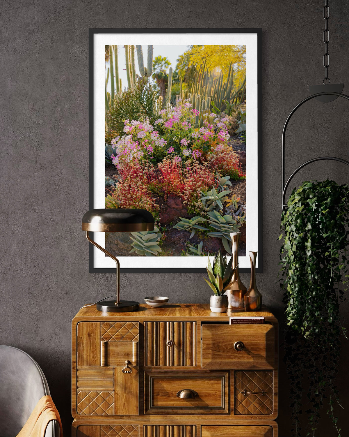 Framed “Cactus Garden II” print displayed above a vintage dresser with cacti, small plants, lamp, and glass bottles.