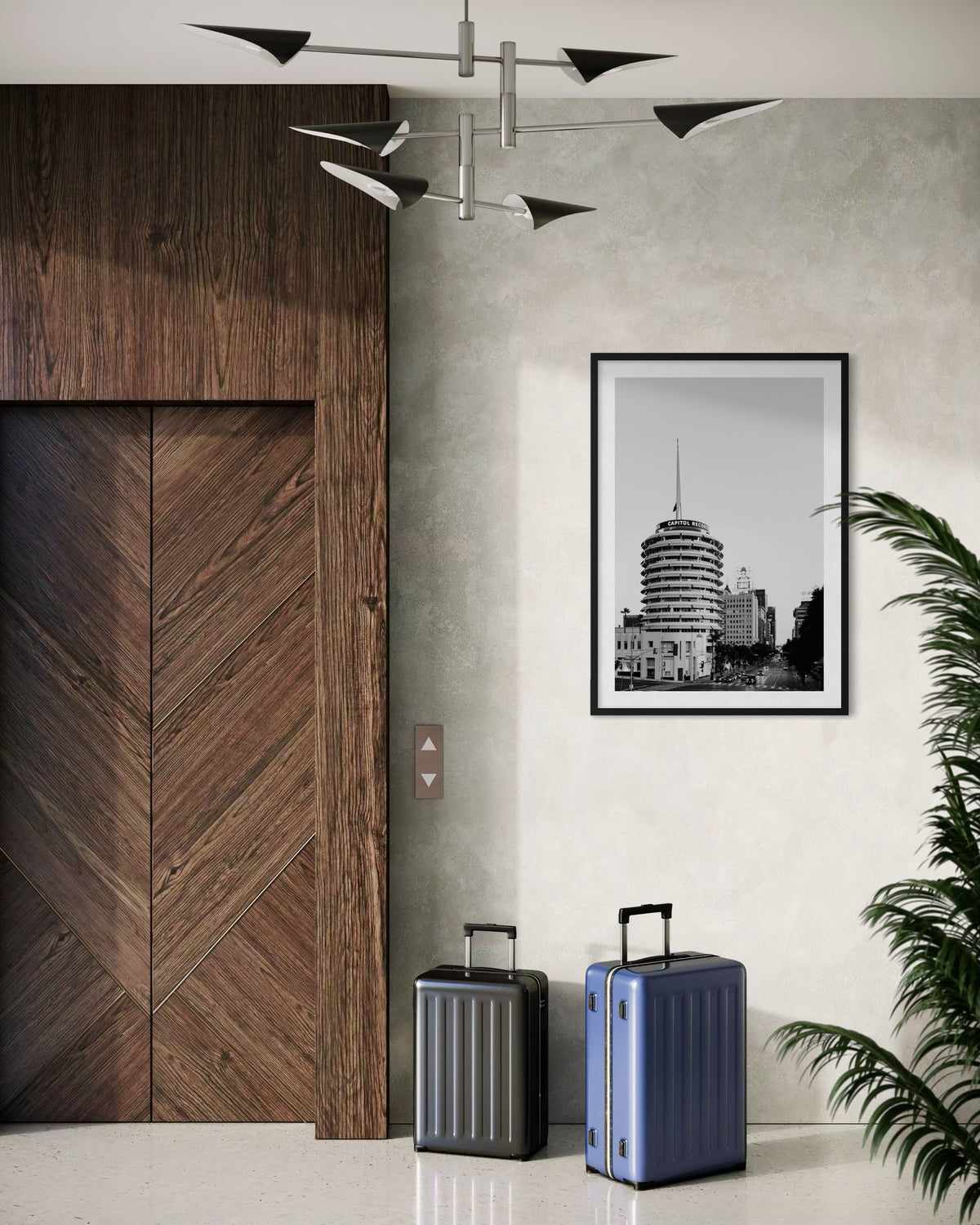 Two suitcases by a wood-paneled elevator; Capitol Records Building photo and a plant suggest Los Angeles location.