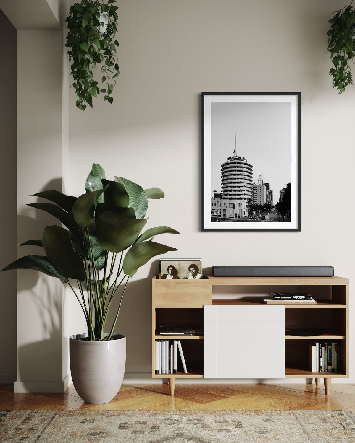 Framed photo of Capitol Records Building, Los Angeles, on console with potted plant and books in living room.