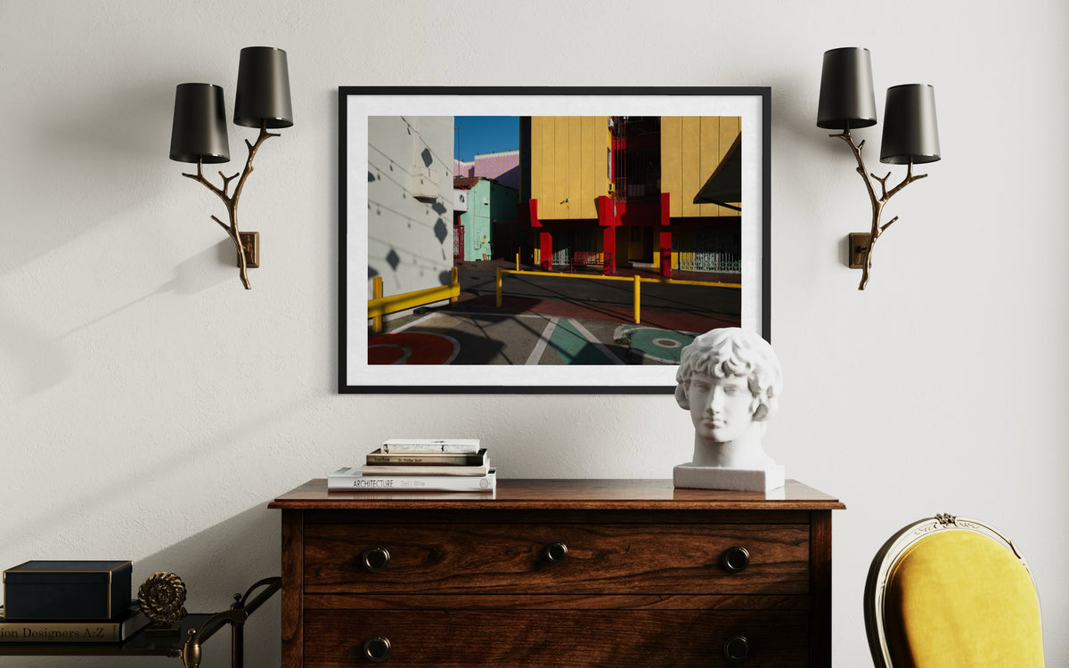Framed “Chinatown Study” LA street photograph displayed above a dresser with decor, sconces, and yellow chair.