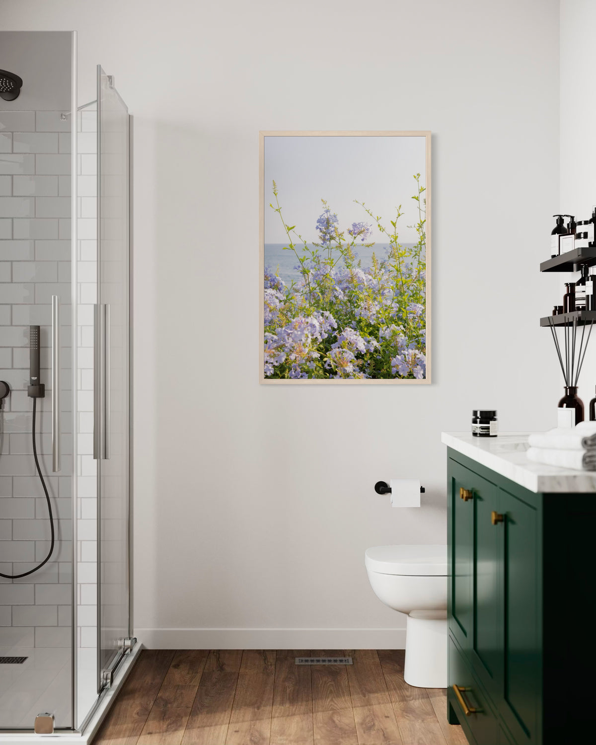 Bright bathroom with a green vanity, glass shower, and “Coastal Flowers” art framed above the toilet on a white wall.