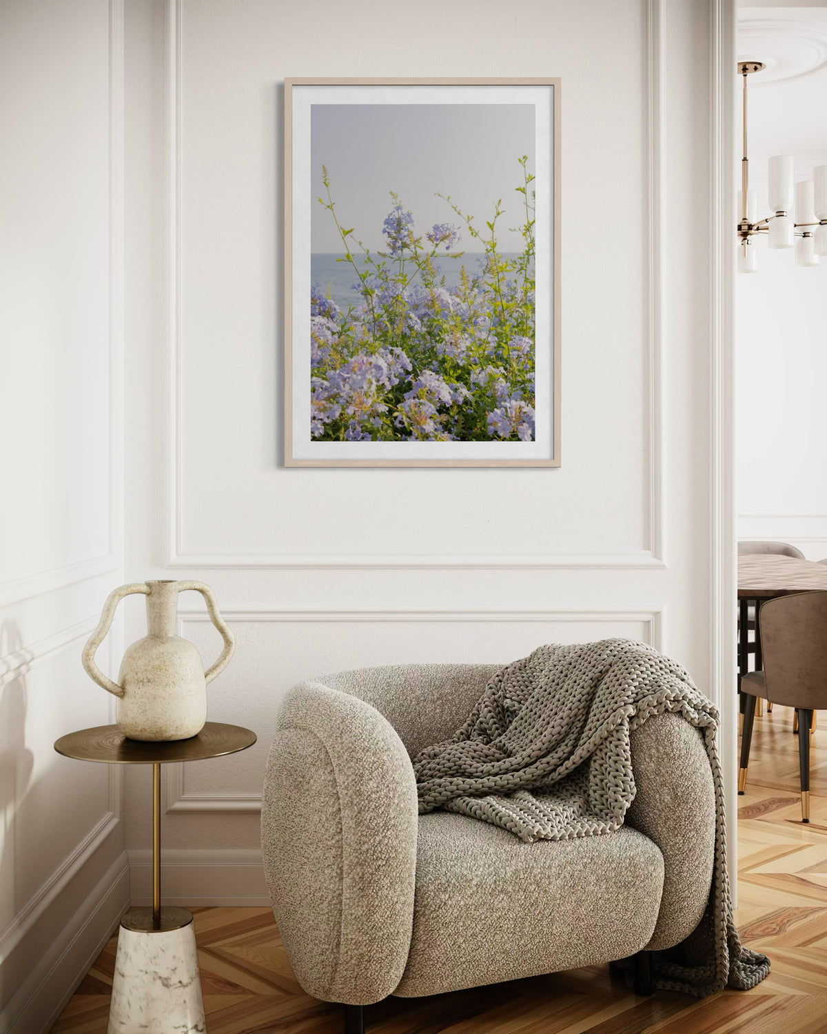 Coastal wildflowers in sunlight; displayed above a beige chair, knit blanket, and side table in a bright room.