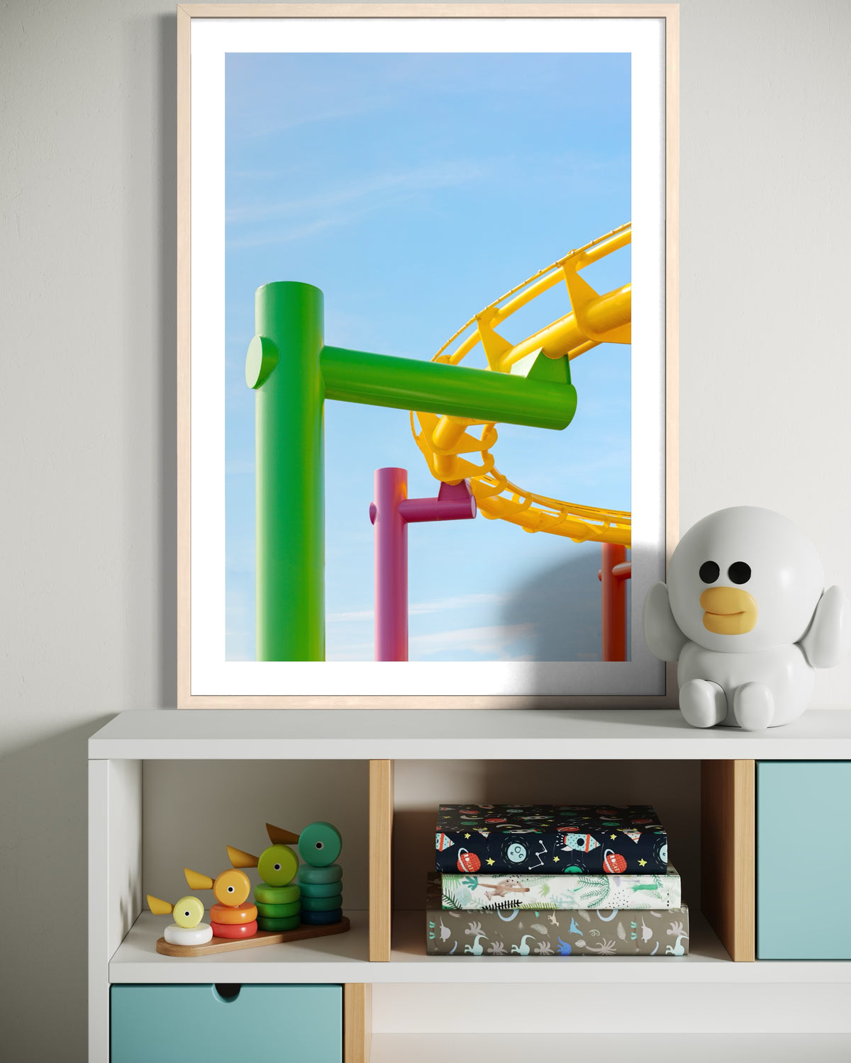 Santa Monica roller coaster print in a frame displayed above a white shelf with toys and folded fabric.
