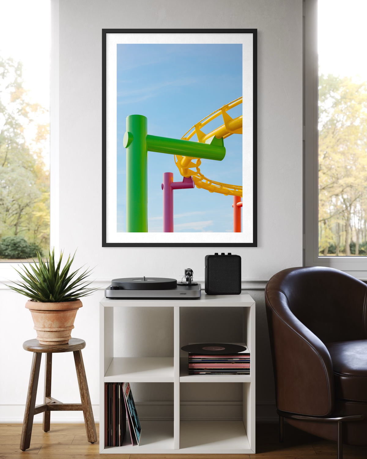 Framed print of Santa Monica roller coaster hangs above a white shelf with a record player and speaker.