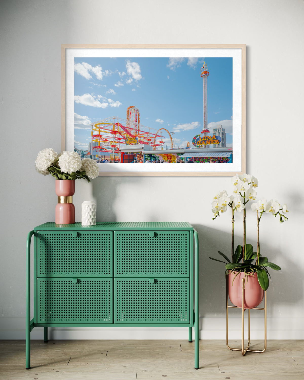 Green console table with plants beneath a “Coney Island Luna Games” photo on a white wall.