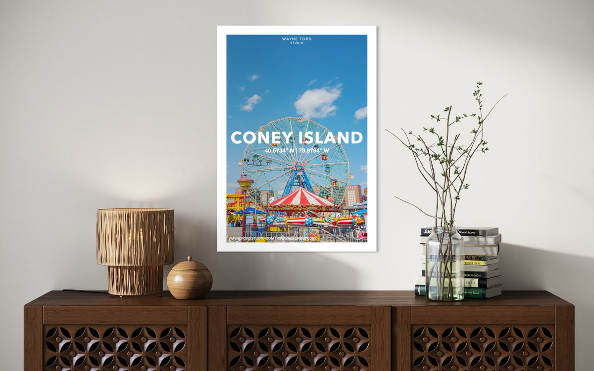 Framed Coney Island Poster No. 03 hangs above a console with lamp, vase, and books in a well-lit room.