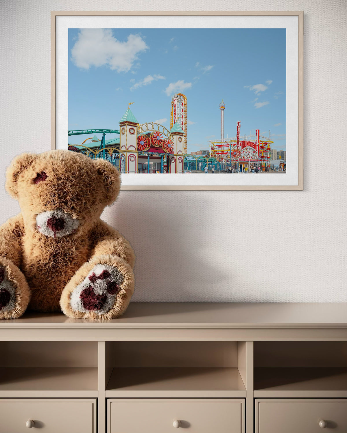 Framed photo of Coney Island Thunderbolt hangs above a cabinet topped with a large teddy bear.