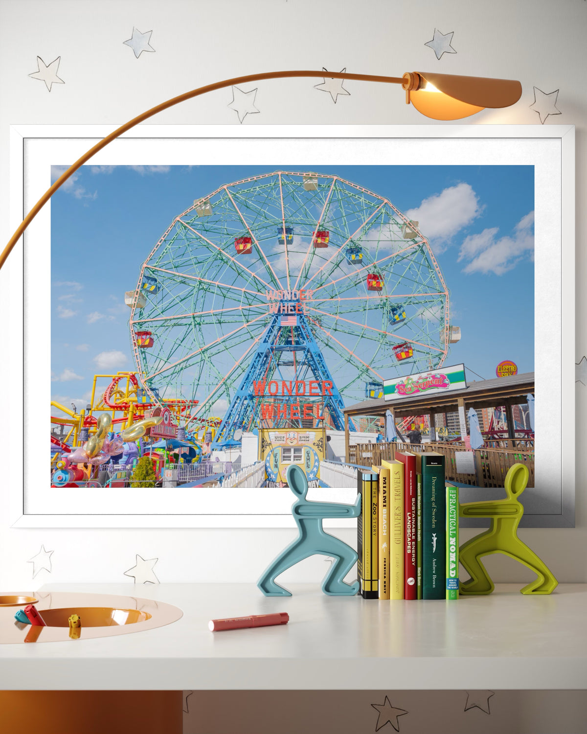 Framed print of the Coney Island Wonder Wheel in Brooklyn displayed on a desk with books, lamp, and figurines.