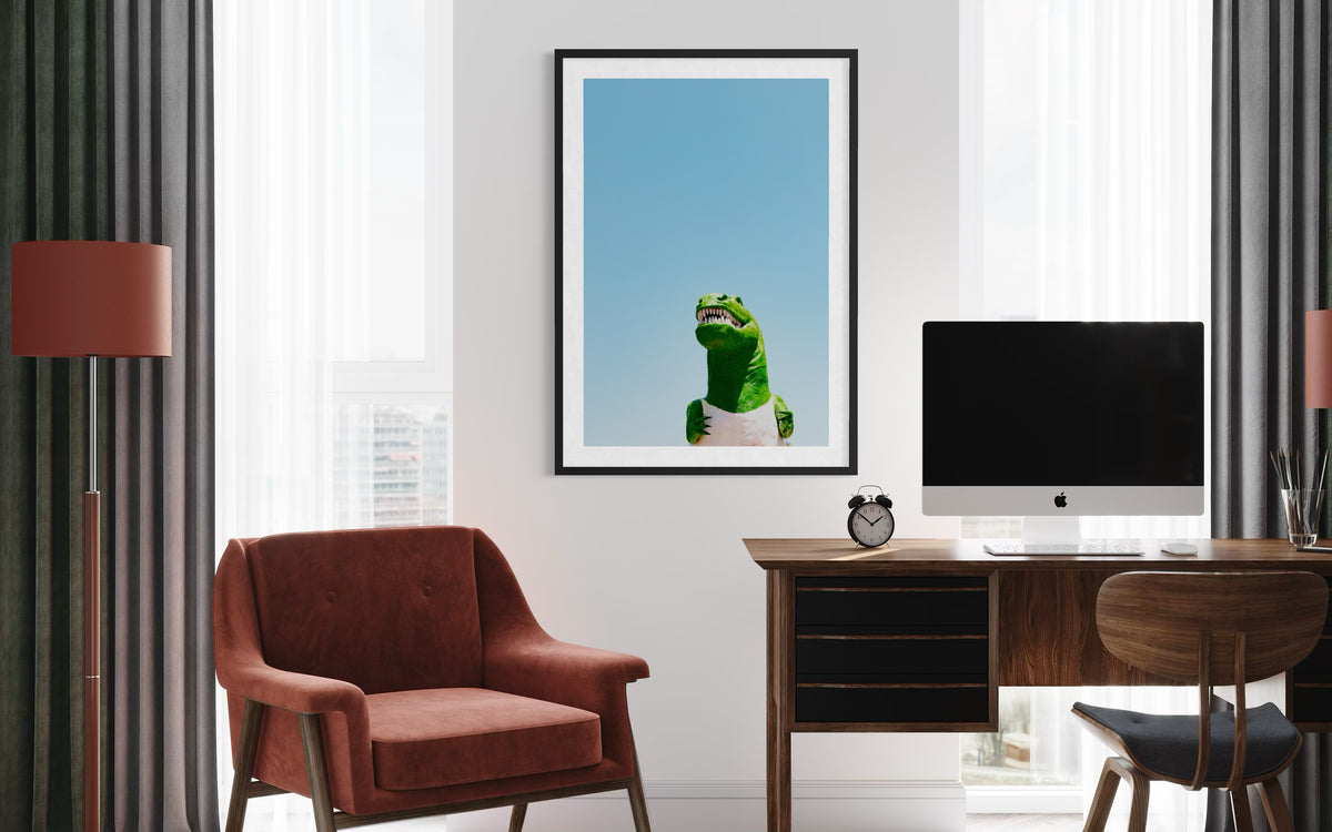 Red chair and desk in a modern office, framed dinosaur art on wall, bright California sky visible through window.