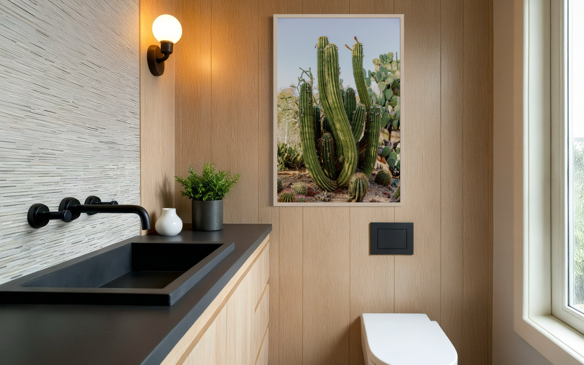 Wood-paneled bathroom with a black sink, succulents, and Elephant Cactus art above a white toilet.