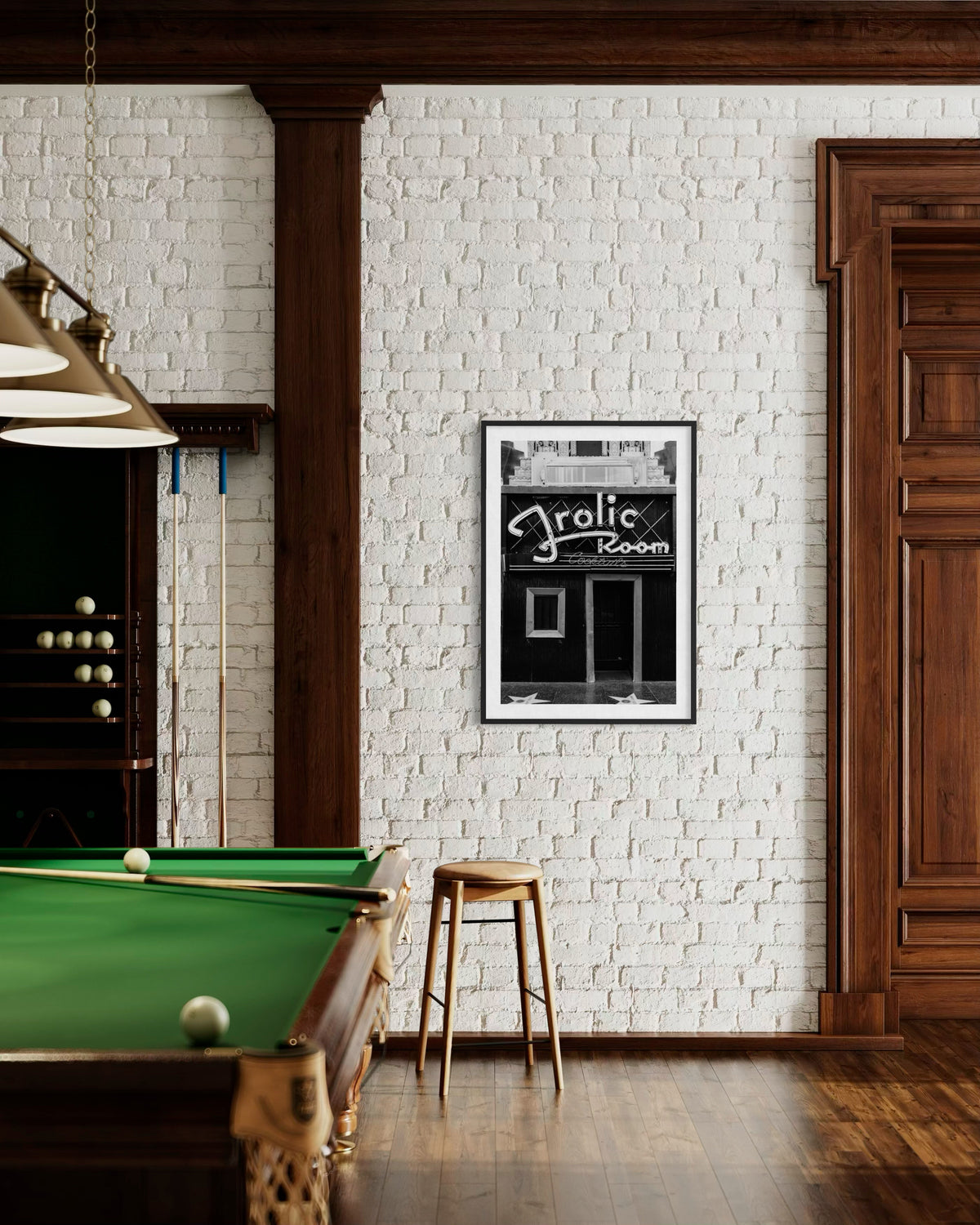 Pool table, wooden stool, and framed Frolic Room sign on a white brick wall in Los Angeles.