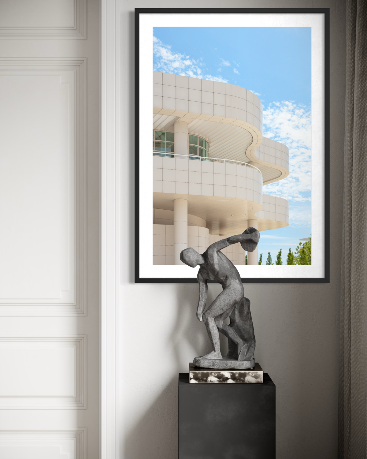 Framed print of Getty Center I hangs above a small, dark discus thrower statue on a pedestal.