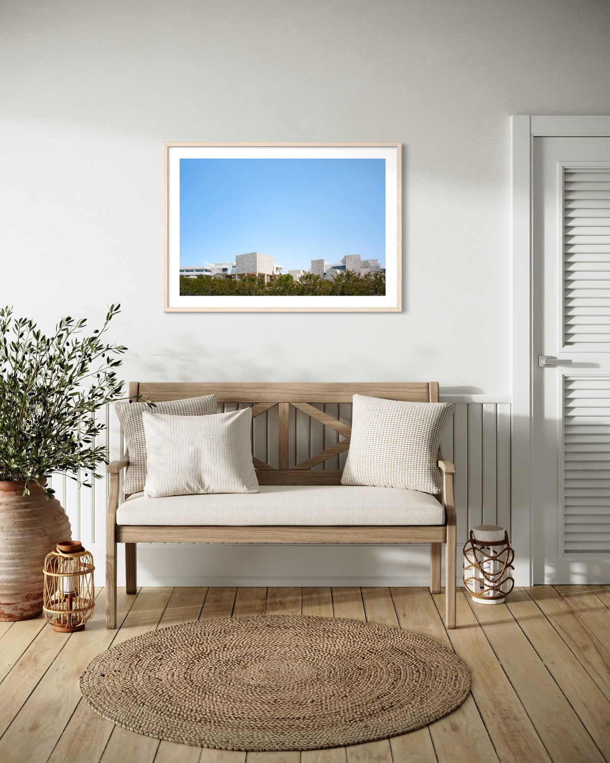 Wooden bench with pillows and travertine accents in entryway; Getty Center III photo framed on the wall.