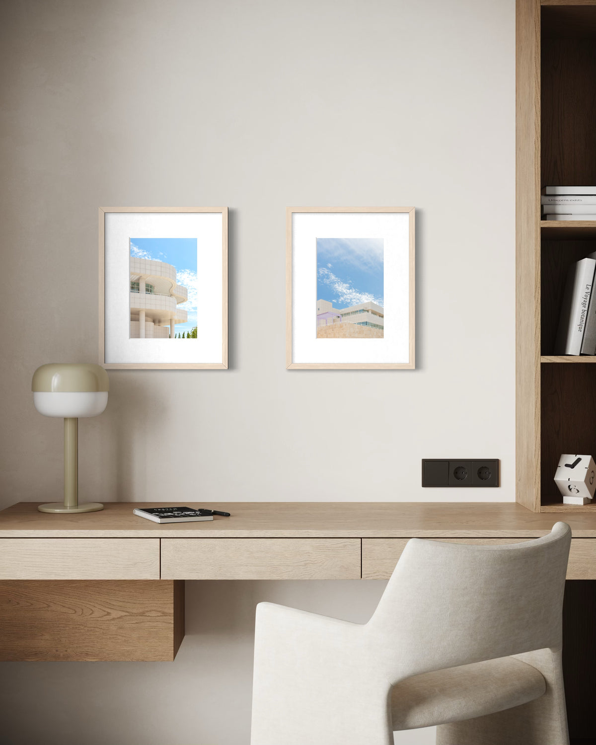 Minimalist desk with white chair and lamp below Getty Center Pairing prints on a beige wall in Los Angeles.