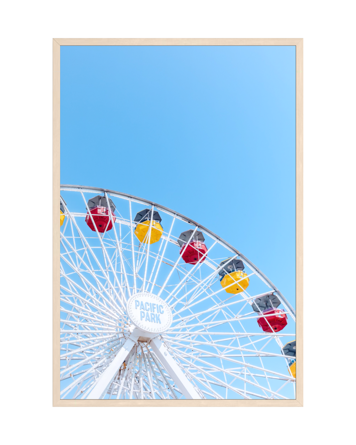A Ferris wheel with red and yellow gondolas set against a summer sky, photographed outdoors.