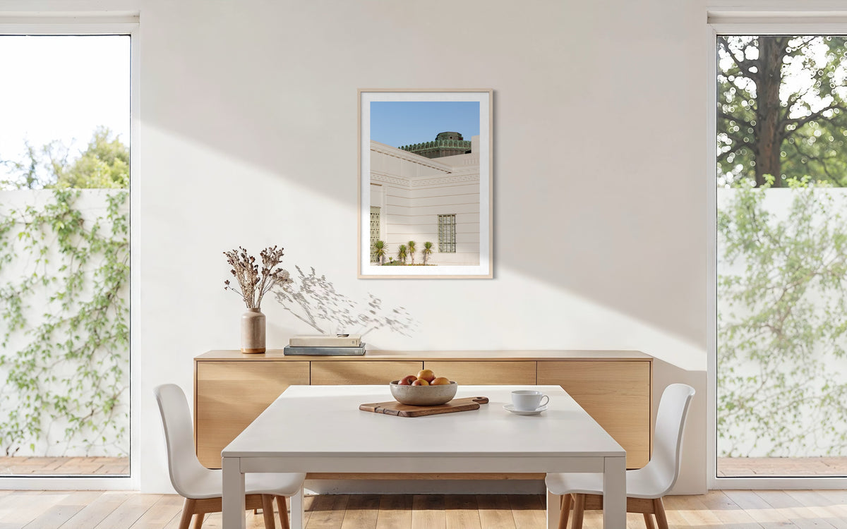 White table and four chairs in a minimalist dining room with framed “Griffith Observatory Moment” artwork.