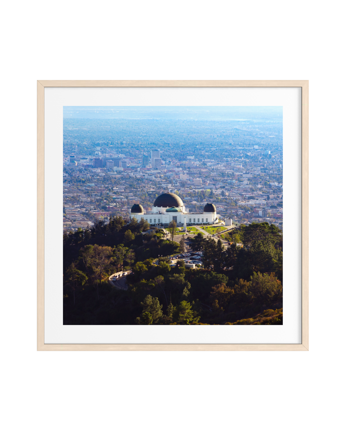 Griffith Observatory on a hill with Los Angeles skyline visible below against a clear sky.