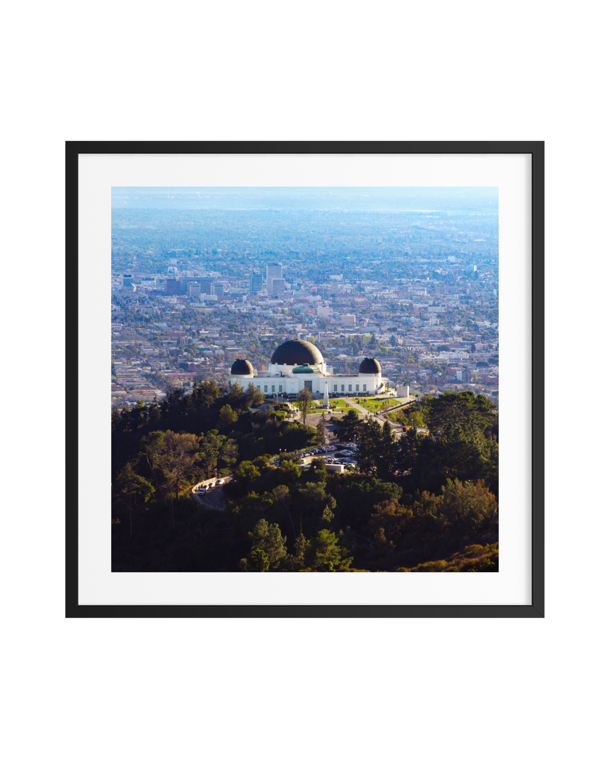 Griffith Observatory seen from above with surrounding trees and Los Angeles cityscape in the background.