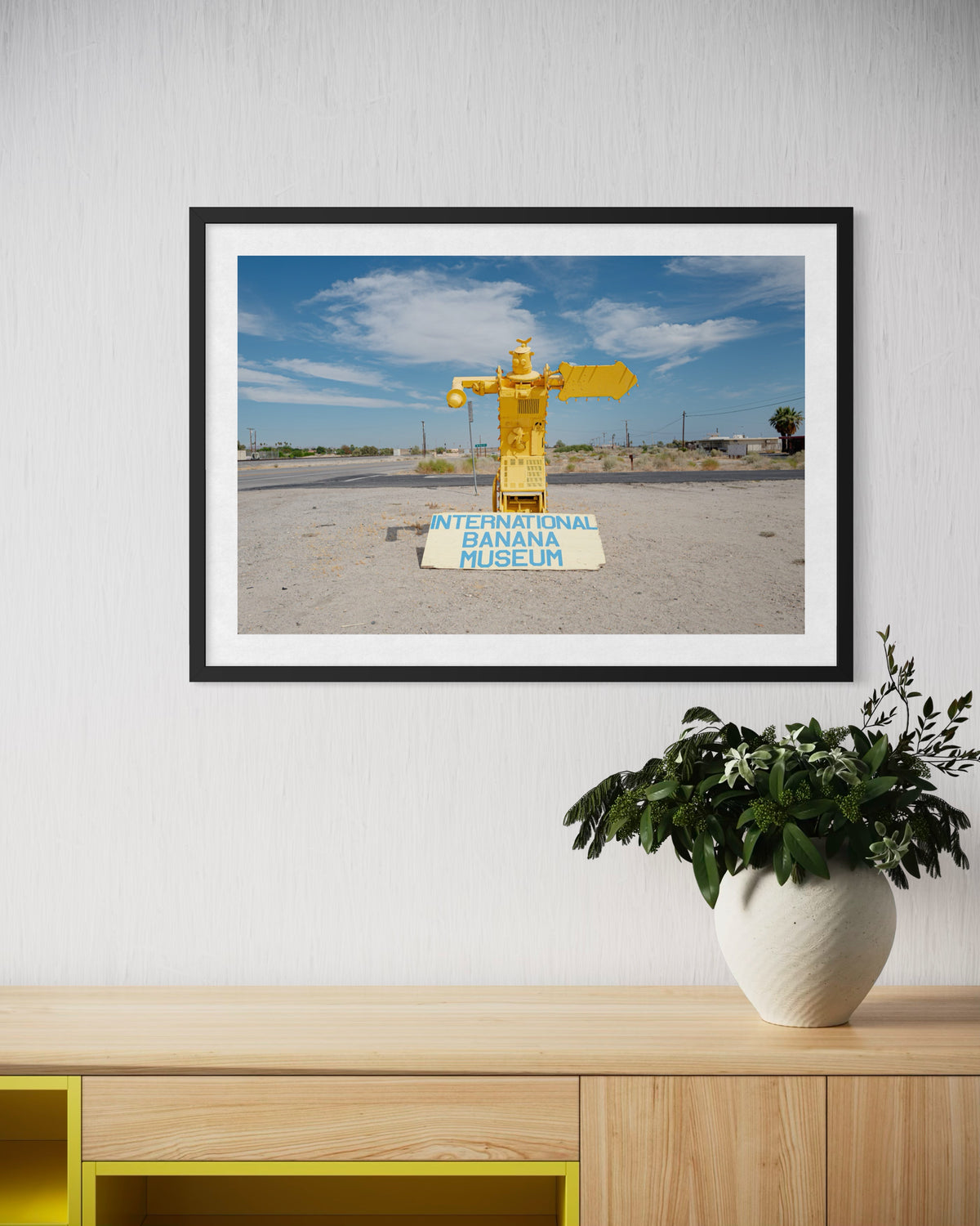 Yellow banana statue at the International Banana Museum near the Salton Sea, framed above a green plant.