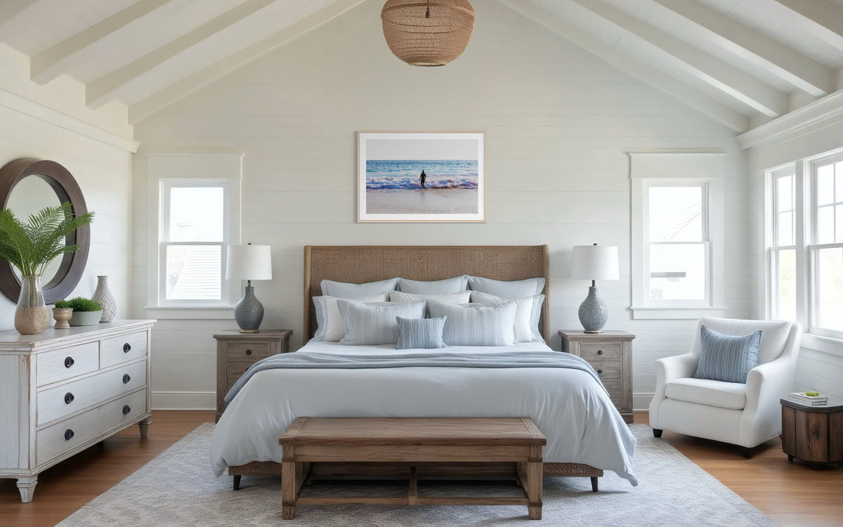 Wooden bed in a bright room with white walls, featuring the Into The Sea sunrise print above the headboard.