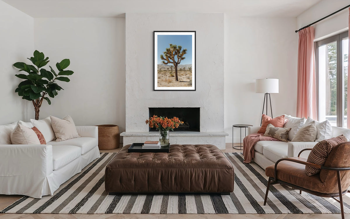 White sofas and plants in a living room; Joshua Tree III artwork is centered above the fireplace.