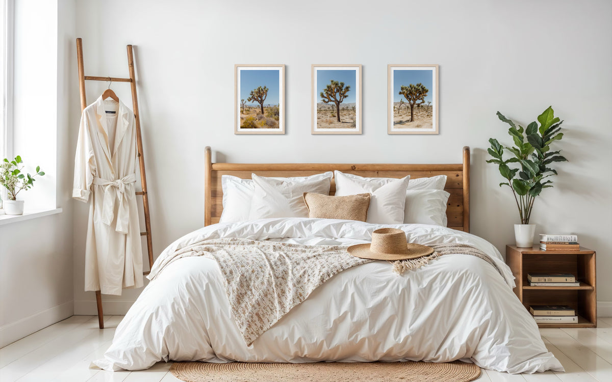 Wooden bed with neutral bedding, plants, and a Joshua Tree print displayed above.