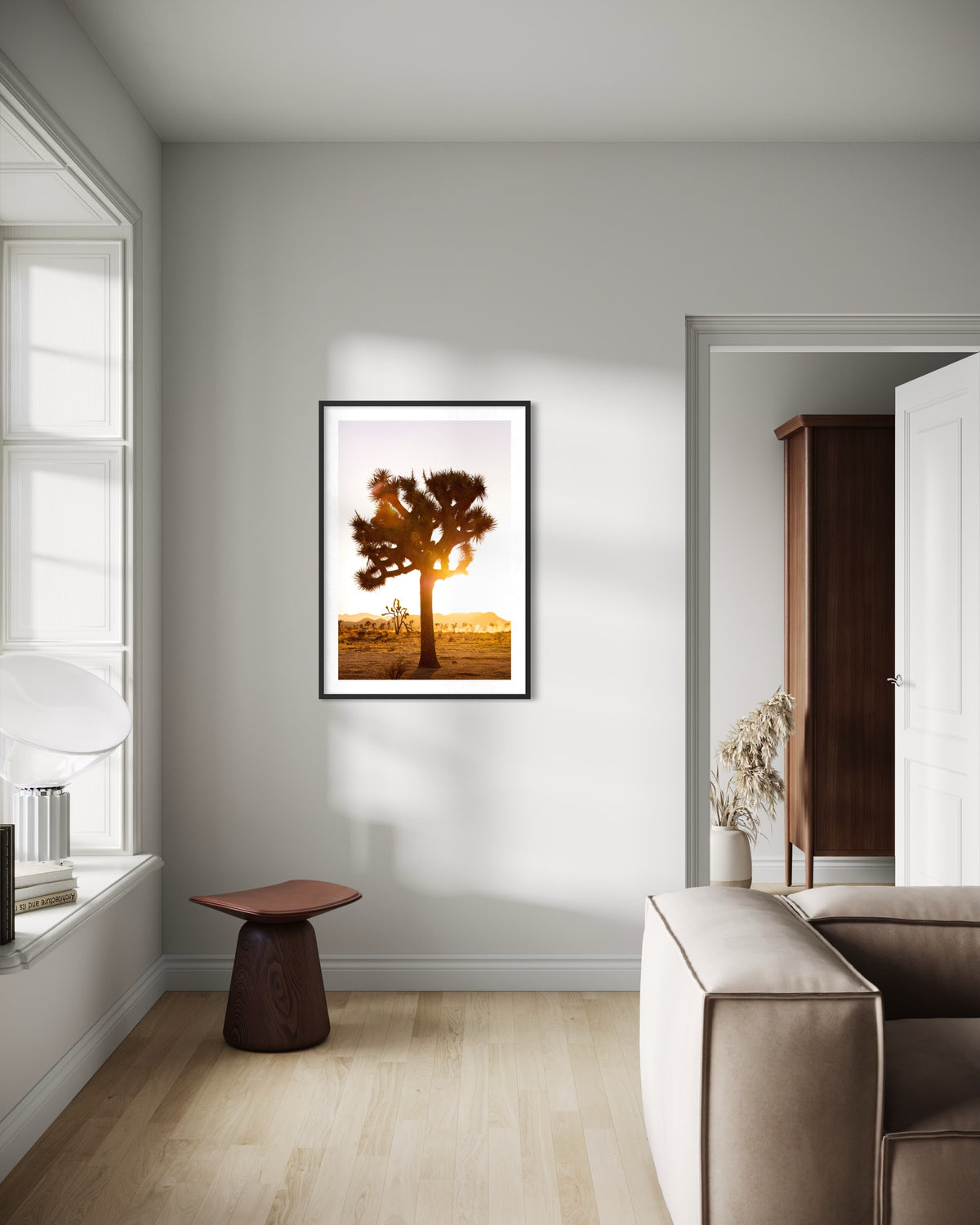 Framed “Joshua Tree Sunset” print displayed on a sunlit wall above a beige sofa with wood accents.