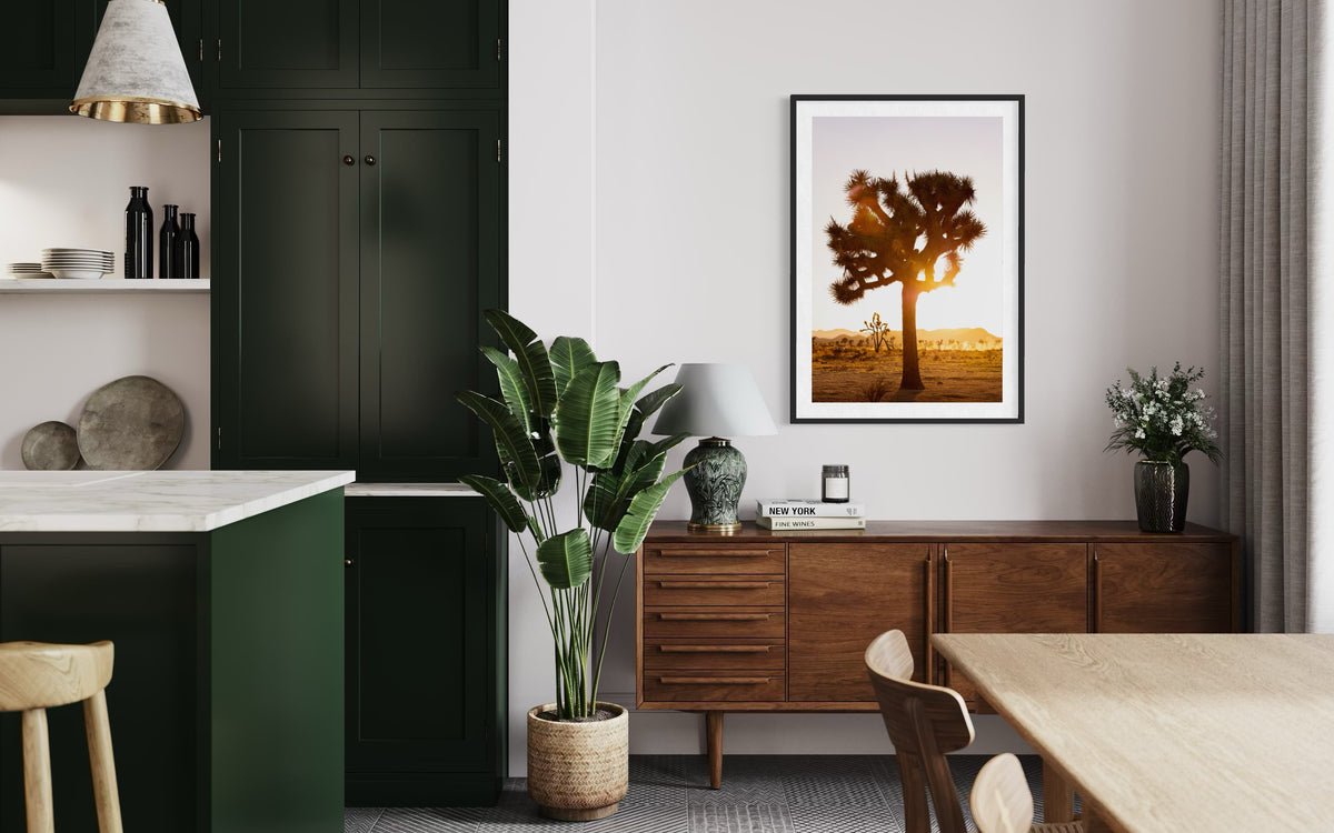 Green cabinets and wood dining set with a framed Joshua Tree sunset photograph hanging on the wall.