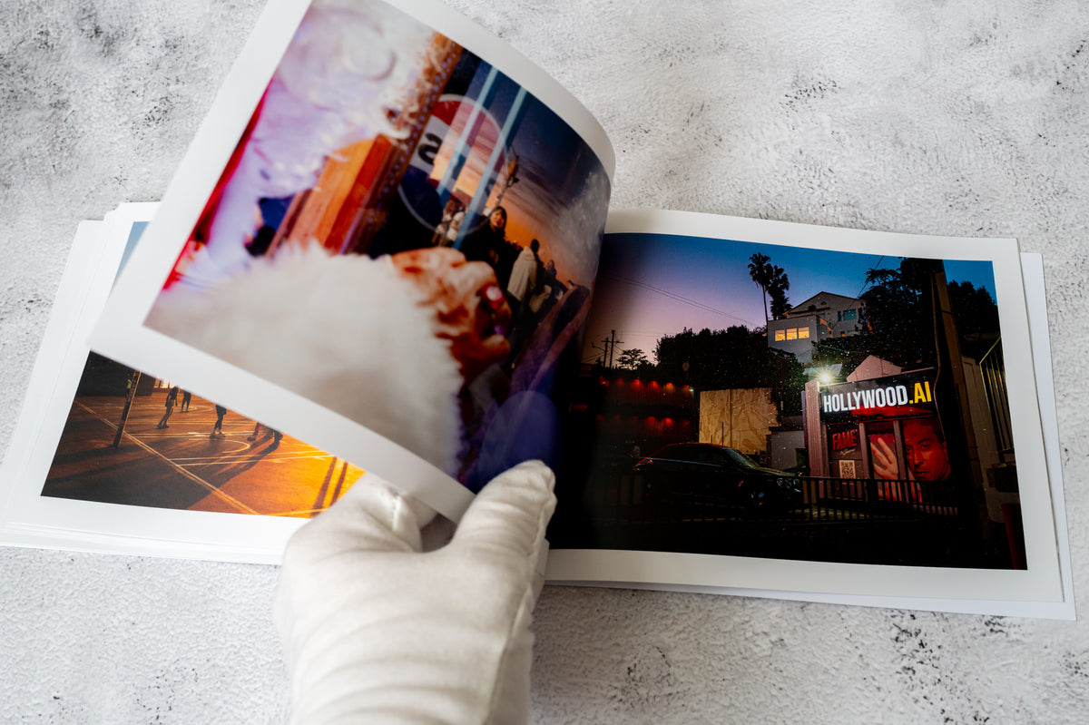 A gloved hand flips through LA / FRAGMENTS No. 1, a zine featuring Los Angeles street photography and art.
