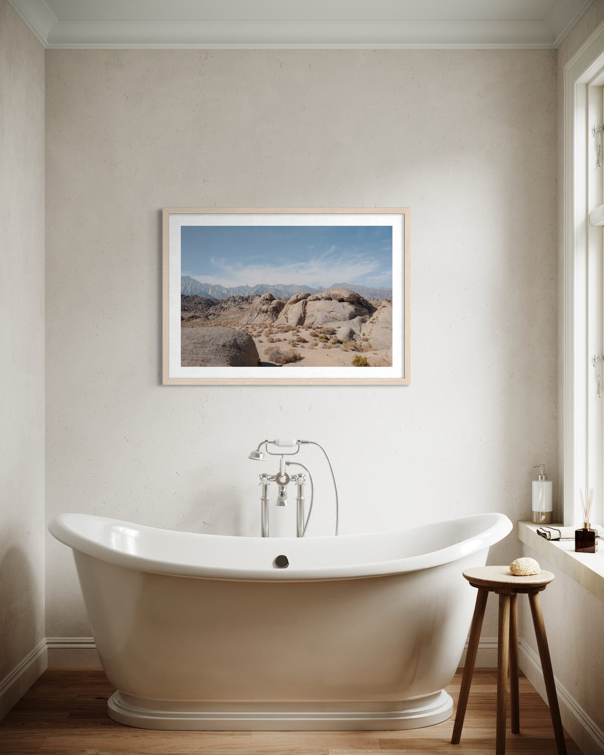 White freestanding tub below a Lone Pine landscape photo in a minimalist bathroom setting.