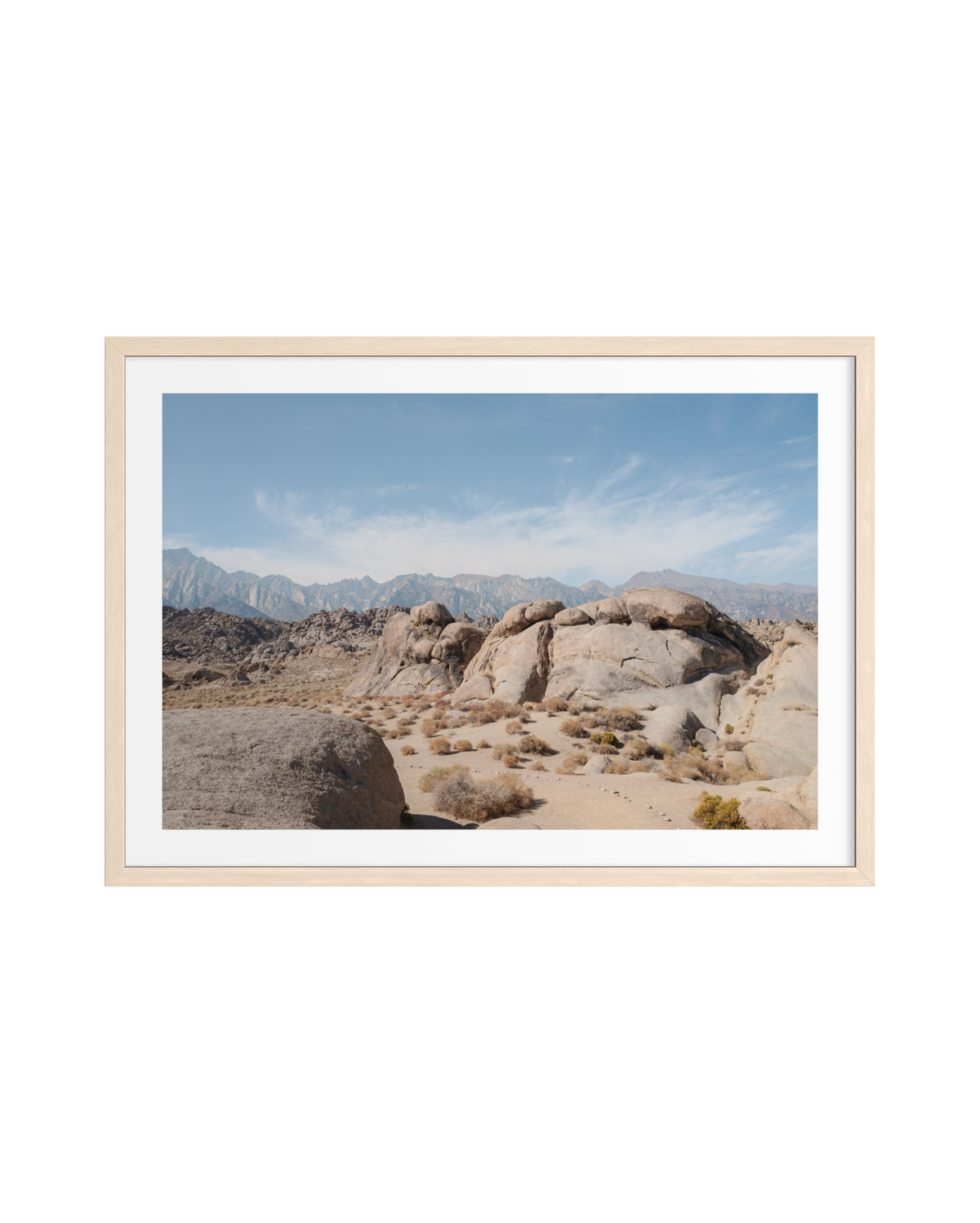 Desert rock formations with distant Sierra Nevada mountains under clear blue sky in Lone Pine, California.