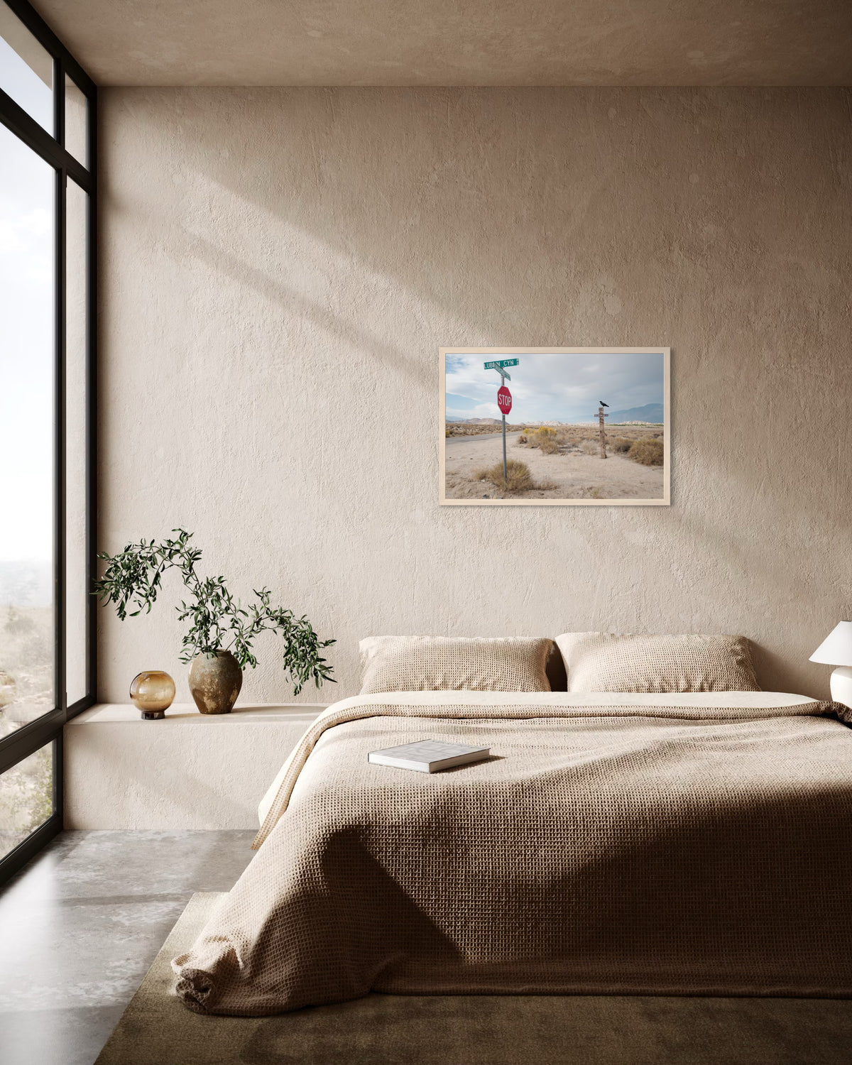 Beige bedding, potted plants, and a Lone Pine Sentinel road sign print displayed on the bedroom wall.