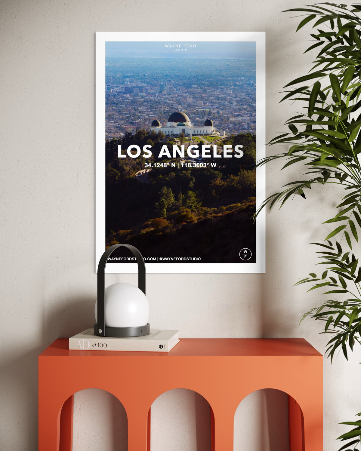 Three posters of Los Angeles, New York City, and Coney Island above an orange table with a lamp and book.