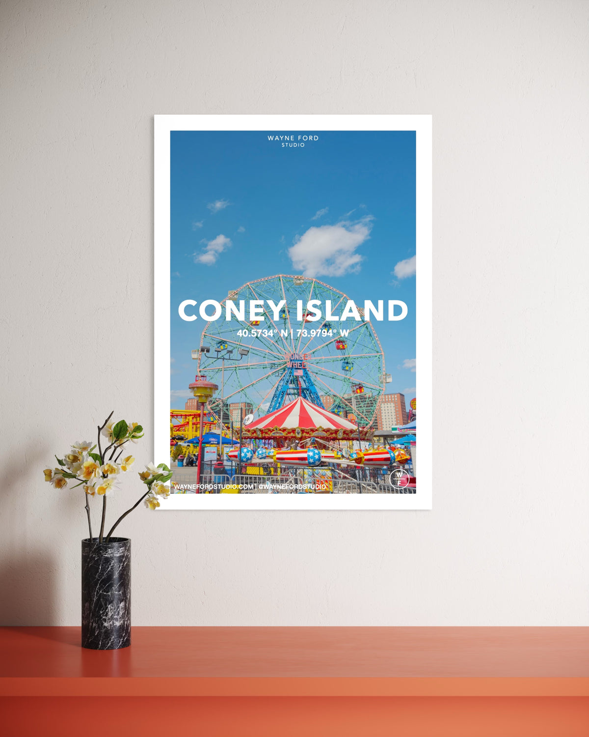 Poster set of Los Angeles, NYC, and Coney Island above an orange table with a black vase of flowers.