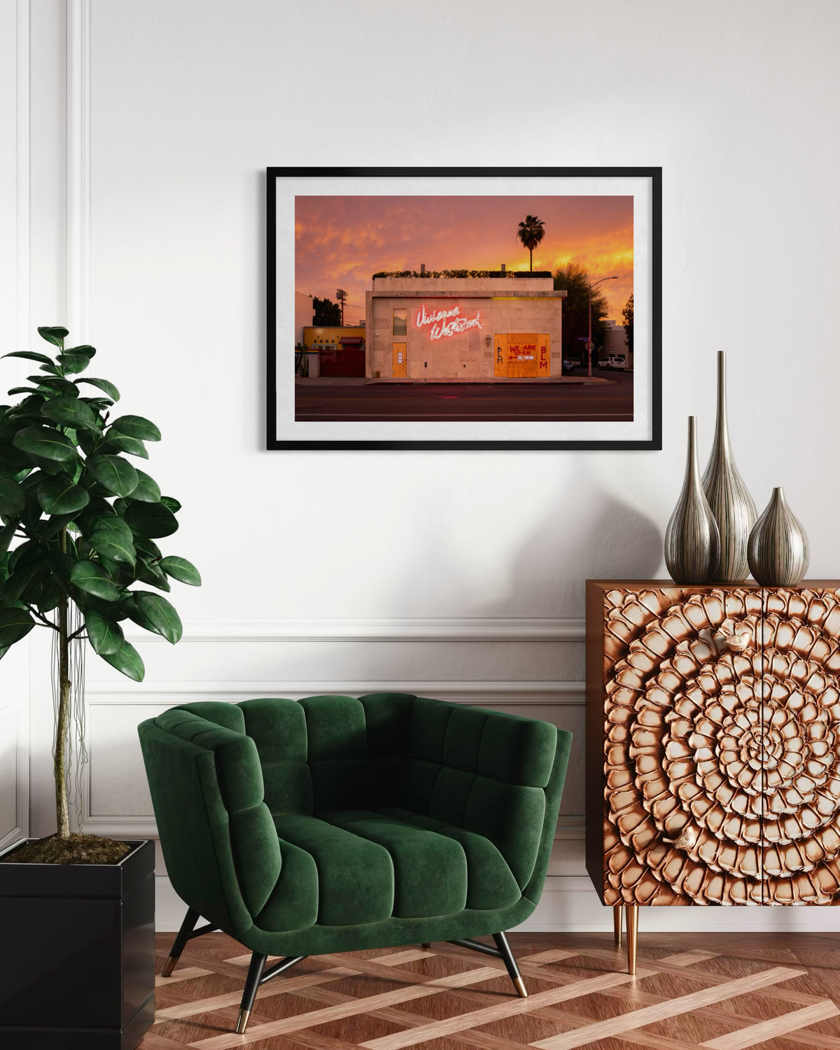 Green velvet chair, wood chest, large plant, and sunset photo in a living room on Melrose Avenue, Los Angeles, 2020.
