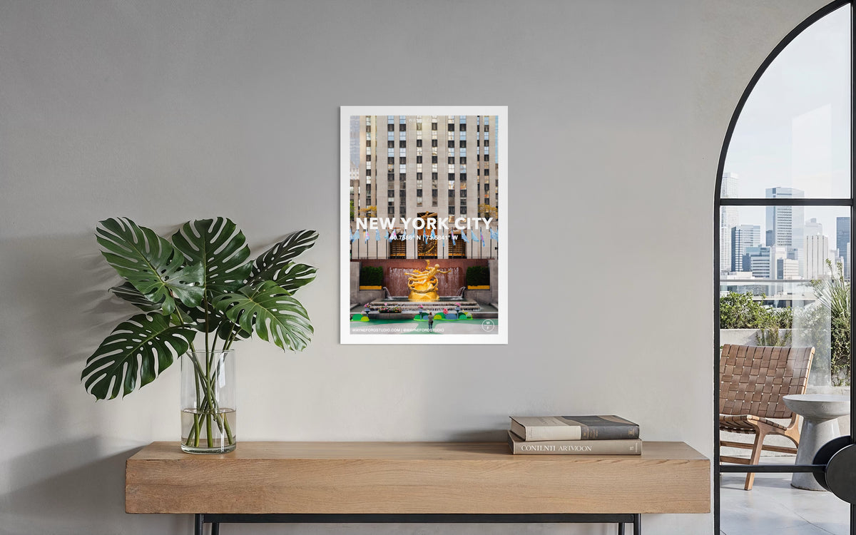 Framed New York City Poster No. 02 displayed above a console with a potted plant at Rockefeller Center.