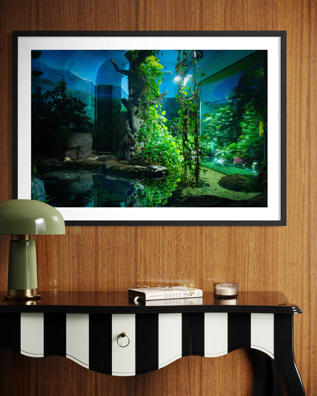 Framed “Night at the Zoo” photo print above a striped table with books and a green lamp in the room.
