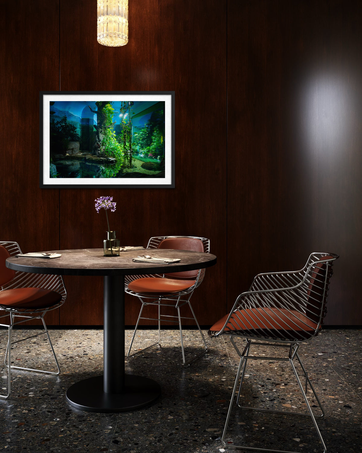 A round table with four chairs, a vase, and art on dark wood under a hanging light at night in the zoo.