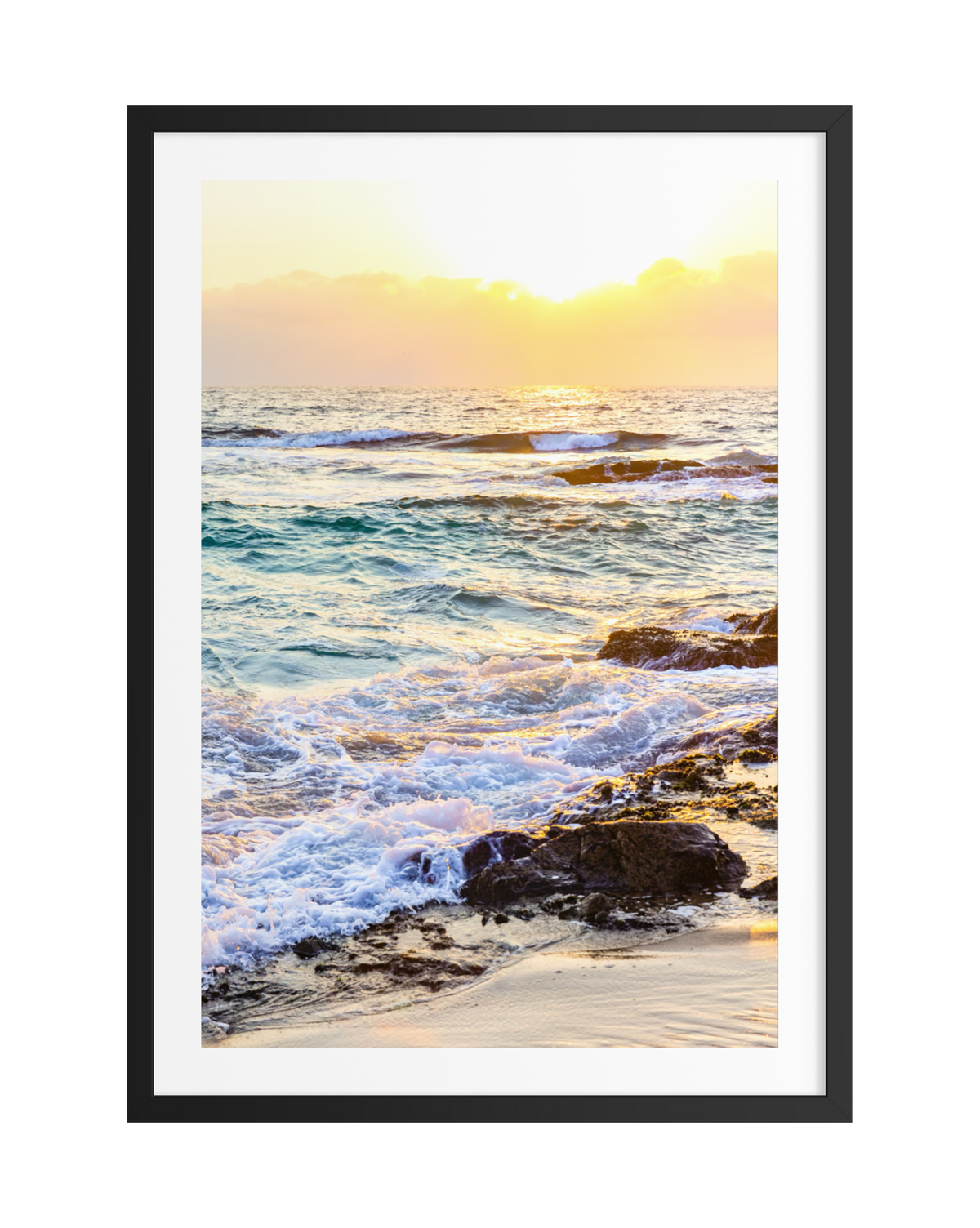 Waves breaking on a rocky shore at sunset, photograph set in a simple black frame.