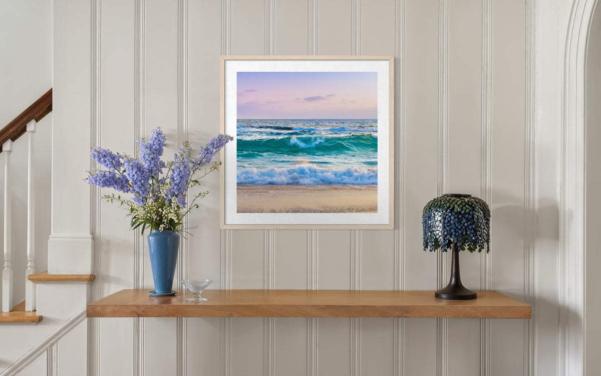 “Ocean Waves II” print displayed above a wooden shelf with a blue vase and beaded lamp in a room setting.