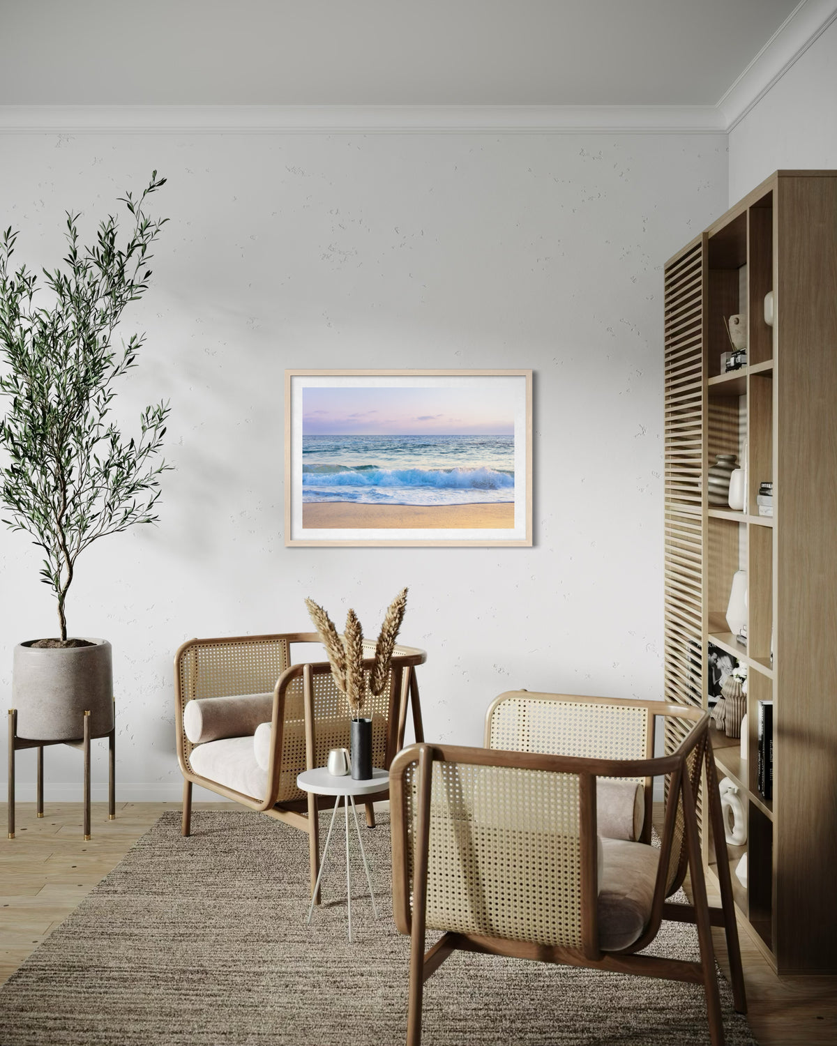 Rattan chairs and a potted plant beside “Ocean Waves” artwork on a white wall in a living room.